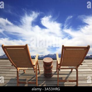 Der komfortable Ort, um die Schönheit der Wolken in Patagonien zu genießen. Zwei zusammenklappbare Holzstühle und ein kleiner Nachttisch auf der Promenade Stockfoto