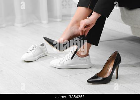 Frau wechselt Schuhe auf Sofa zu Hause, Nahaufnahme Stockfoto
