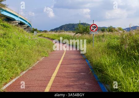 Gwangju, Südkorea - 24. September 2020: Ein kurvenreicher Abschnitt des Yeongsan River Radweges verläuft parallel zu einer Autobahnüberführung, mit einer No-Littteri Stockfoto