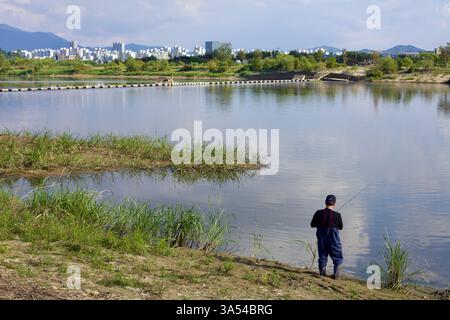 Gwangju City, Südkorea - 24. September 2020: Ein Fischer steht am Ufer des Yeongsan River und wirft seine Linie in die ruhigen Gewässer. Die r Stockfoto