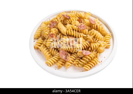Fusilli Carbonara Nudeln mit knusprigen Speckstückchen und Parmesan auf einem Teller isoliert auf weißem Hintergrund. Stockfoto