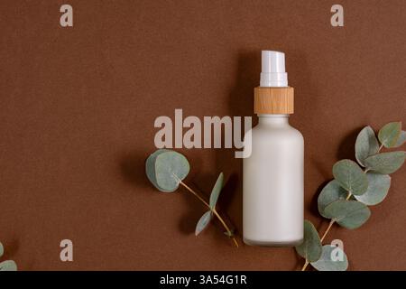 Gesichts- oder Körpercreme in weißer Milchglasflasche mit natürlichen Eukalyptusextrakten und Ölen. Hautpflegekosmetik. Pflanzliche Behandlung. Stockfoto