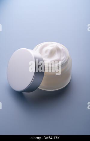 Nahaufnahme von Kollagencreme im offenen Glasgefäß und silbernem Deckel auf grauem Hintergrund. Präsentation von Hautpflegeprodukten. Swirl Sahne, Promotion p Stockfoto