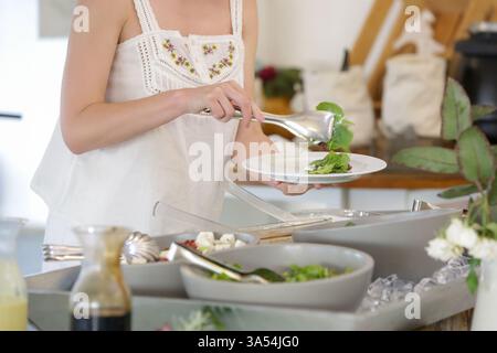 Eine Frau, die Essen von einem Buffet nimmt Stockfoto