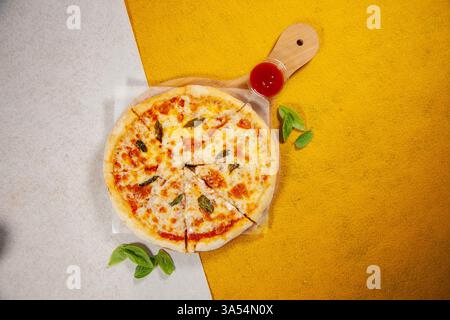 Pizza Margarita auf einem runden Holzteller mit gelbem und weißem Hintergrund. Stockfoto