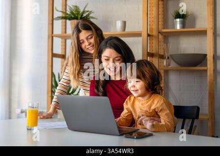 Frau genießt digitale Geräte mit ihren Kindern und verbringt lustige Momente zu Hause. Stockfoto