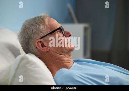 Ruhender älterer Mann in Krankenhausbettwäsche Stockfoto