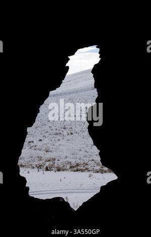 Höhle auf dem Felsen. Eingang und Fenster der Höhle. Wunderschöne Aussicht von der Höhle. Geheimes Fenster im Winter. Foto aus der Höhle Stockfoto