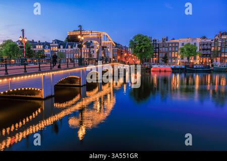 Amsterdam bei Nacht in Holland mit hellen Lichtern der Stadt mit seinen Kanälen und alten Uferhäusern und Brücken - ein Reisebild Stockfoto