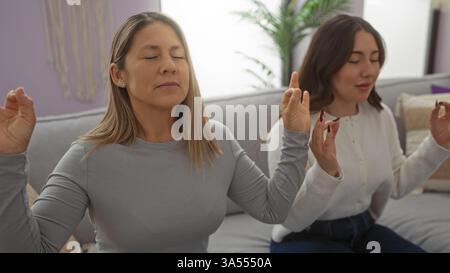 Mutter und Tochter üben gemeinsam Meditation in einem gemütlichen Wohnzimmer und verkörpern Liebe und Gelassenheit in einer familiären Wohnung. Stockfoto