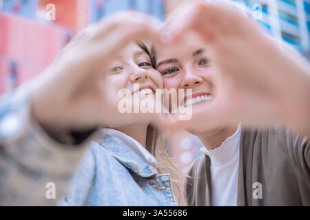 Glückliche kaukasische Freunde, die mit Händen und Lächeln im Freien eine Herzform machen Stockfoto