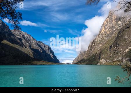 Ein atemberaubender türkisfarbener See reflektiert den blauen Himmel, eingebettet zwischen hoch aufragenden Bergen. Die friedliche Landschaft ist Teil der berühmten Laguna 69 Trek in Hu Stockfoto