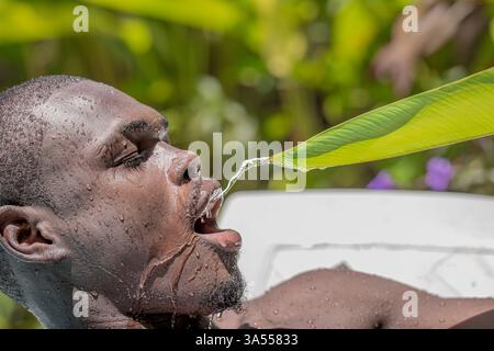 Schwarzer Mann trinkt Wasser aus Leaf Stockfoto