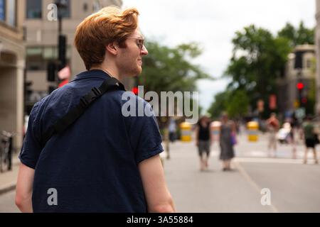 Ein junger Mann mit roten Haaren geht durch eine geschäftige Stadtstraße Stockfoto