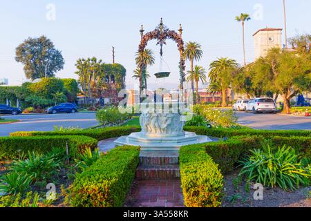 Los Angeles, Kalifornien - 10. Januar 2025: Ruhiger Brunnen befindet sich im Zentrum von gepflegten Hecken, eingerahmt von Palmen und historischer Architektur Stockfoto