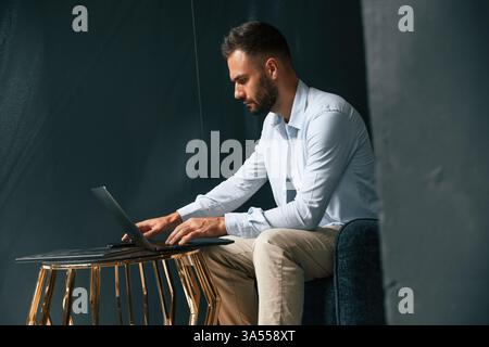 Fokussiert, selbstbewusst. Geschäftsmann sitzt und arbeitet mit Laptop. Stockfoto