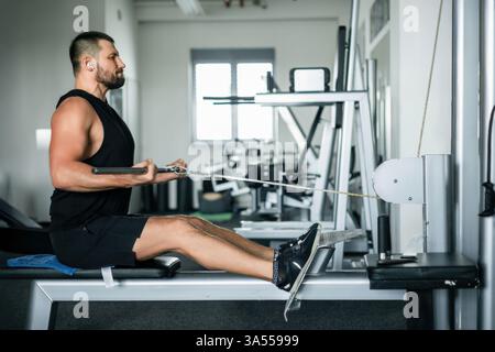 Sportliches Manntraining auf einer Kabelreihenmaschine in einem modernen Fitnessstudio Stockfoto