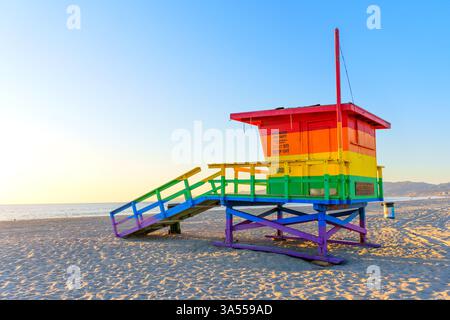 Venice Beach, Kalifornien - 16. Januar 2025: Lebendiger, regenbogenfarbener Rettungsschirm-Turm steht am Venice Beach, beleuchtet von warmem Sonnenuntergang, Showcas Stockfoto