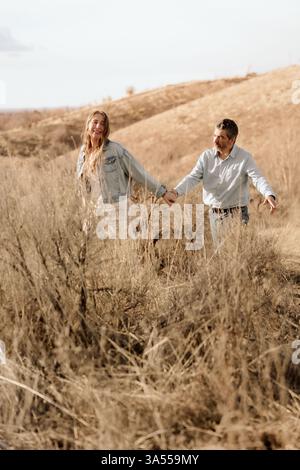Ein Paar geht Hand in Hand und erkundet gemeinsam einen sonnendurchfluteten Hügel Stockfoto