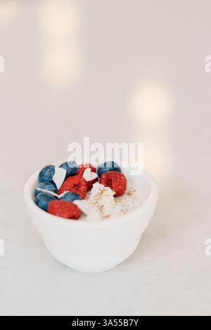Eine minimalistische Schüssel Kokosjoghurt mit Beeren und Zimt Stockfoto