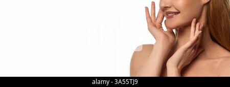 Zugeschnittenes Bild einer jungen, eleganten Frau, die sanft das Gesicht berührt und eine gepflegte, strahlende Haut vor weißem Hintergrund zeigt. Stockfoto