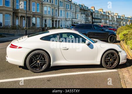 Eleganter weißer Sportwagen porsche 911, der an einem sonnigen Tag in tynemouth, Nord-tyneside, großbritannien, auf der Terrasse von percy geparkt wurde Stockfoto