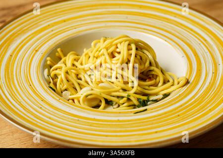 Eine wunderschön überzogene Portion Spaghetti Aaglio e olio, garniert mit frischer Petersilie und dünn geschnittenem Knoblauch. Die Pasta glitzert mit Olivenöl und h Stockfoto