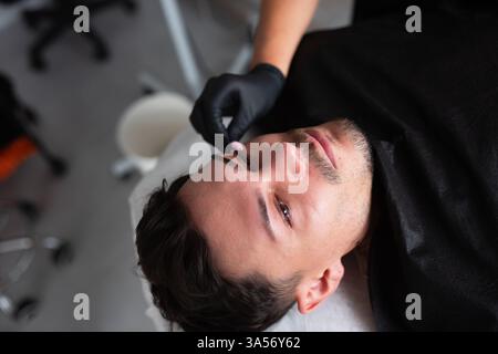 Ein Mann in einem Schönheitssalon kümmert sich um seine Gleichaltrigen. Stockfoto