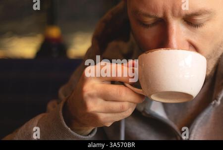 Junger Mann, der Kaffee an einem gemütlichen Ort genießt Stockfoto