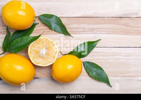 Frische reife Zitronen mit Blättern auf Holztisch. Zitrusfrüchte Stockfoto