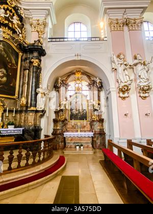 Das Innere einer Kirche mit einem großen Altar und einem Gemälde einer Frau und eines Kindes. Der Altar ist von Bänken und einem roten Teppich umgeben Stockfoto