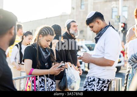 Jerusalem, Israel – 16. März 2025. Ein junger Mann und eine Frau in passenden Hosen schauen sich ihre Handys an, stehen auf einem Gehweg. Stockfoto