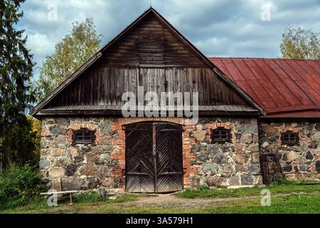 Alte Scheune aus Steinen und Ziegeln, mit großen Holztoren und kleinen Fenstern. Stockfoto