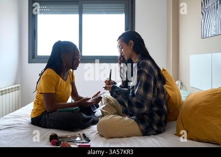 Zwei Studentinnen studieren zusammen, teilen Notizen und lernen im Schlafzimmer Stockfoto