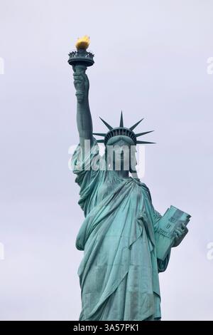 Die Freiheitsstatue erhebt sich majestätisch über dem New Yorker Hafen, einem zeitlosen Leuchtturm der Freiheit, Hoffnung und des anhaltenden amerikanischen Geistes. Stockfoto