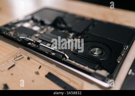 Nahaufnahme von oben auf zerlegtem Laptop auf Holztisch in der Reparaturwerkstatt, mit verschiedenen Komponenten und Schrauben verstreut. Stockfoto
