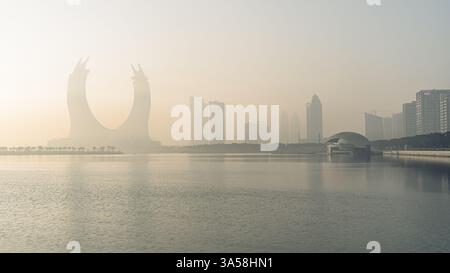 Doha, Katar [24. Februar 2025]: Ein nebeliger Morgen in Doha mit Wolkenkratzern, die teilweise im Nebel verborgen sind und eine geheimnisvolle und ruhige Stadtlandschaft schaffen. Stockfoto