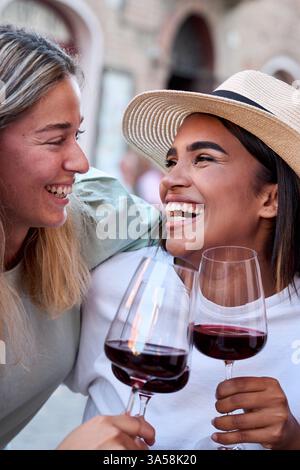 Drei glückliche Freundinnen, die draußen in der italienischen Stadt mit Rotwein tosten Stockfoto