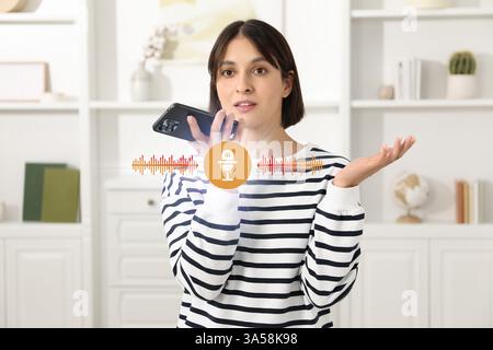 Junge Frau, die zu Hause Sprachnachrichten per Smartphone aufnimmt. Abbildung: Mikrofon und Schallwellen Stockfoto