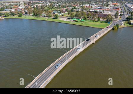 Aus der Vogelperspektive einer langen Brücke über einen braunen See zu einer ländlichen Stadt an der Küste bei Yarrawonga im Norden von Victoria, Australien. Stockfoto