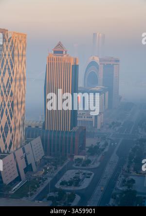 Doha, Katar [24. Februar 2025]: Ein nebeliger Morgen in Doha mit Wolkenkratzern, die teilweise im Nebel verborgen sind und eine geheimnisvolle und ruhige Stadtlandschaft schaffen. Stockfoto