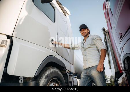 Öffnen der Tür. Der Lkw-Fahrer befindet sich in der Nähe des Transports im Freien. Stockfoto