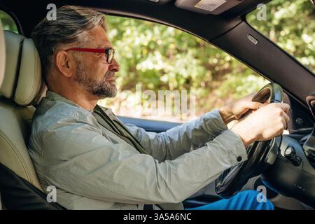 Seitenansicht eines älteren Mannes, der ein Auto fährt. Stockfoto