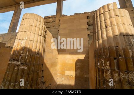 Ruinen von alten Stadtmauern und Säulen an der Stufenpyramide von Djoser. Detaillierte Ansicht der verwitterten Steinstrukturen in Sakkara, Ägypten. Stockfoto