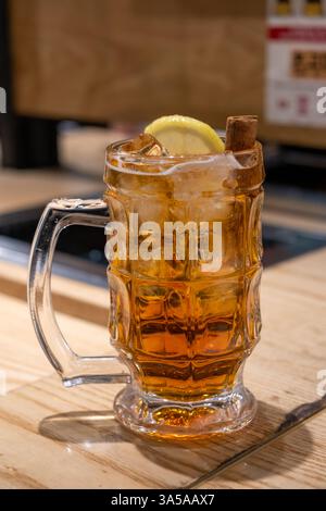 Ein Glas Whiskey mit Zitrone und Zimt auf dem Tisch Stockfoto