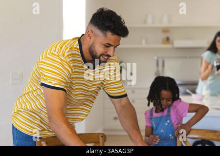 Vater und Tochter legen einen Tisch in der Küche, während Mutter Essen zubereitet Stockfoto