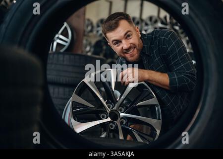 Ich schaue durch das Loch im Reifen. Mann Arbeiter ist Wartungsstation mit Rädern. Stockfoto