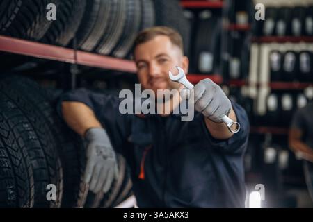 Der Schlüssel liegt in der Hand. Der Arbeiter ist eine Wartungsstation mit Reifen, Rädern. Stockfoto