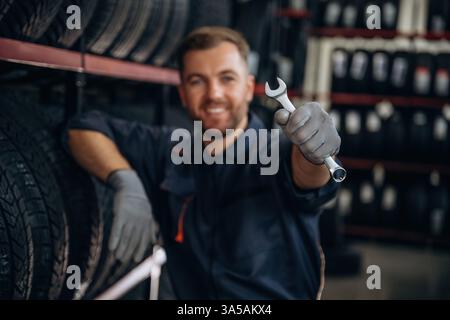 Der Schlüssel liegt in der Hand. Der Arbeiter ist eine Wartungsstation mit Reifen, Rädern. Stockfoto