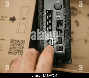 Paris, Frankreich - 11. Februar 2025: Eine Nahaufnahme einer Hand eines Technikers, die ein Kabel in den 10G-Anschluss einer neuen Orange Livebox 7 einführt, zeigt detailliertes r Stockfoto